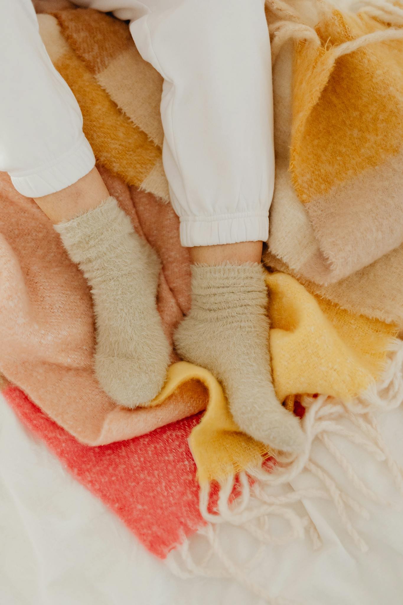 Warm fuzzy socks and a colorful blanket create perfect cozy vibes on a relaxing day indoors.
